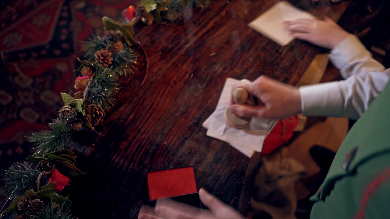 Envelopes for children at Christmas. Elf putting seal on the envelope quickly. Fairy hero making Christmas seal on envelopes.