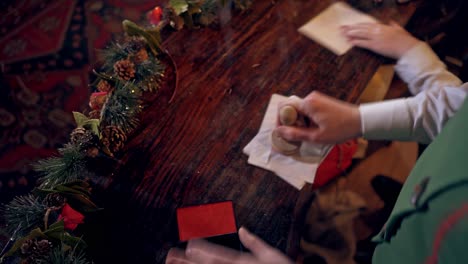 envelopes for children at christmas. elf putting seal on the envelope quickly. fairy hero making christmas seal on envelopes.
