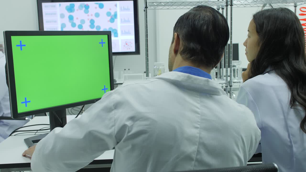dos científicos de investigación médica mirando la pantalla verde en el laboratorio moderno