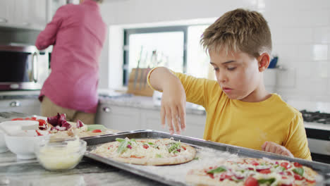 Feliz-Abuelo-Caucásico-Y-Nieto-Haciendo-Pizza-En-La-Cocina,-Cámara-Lenta