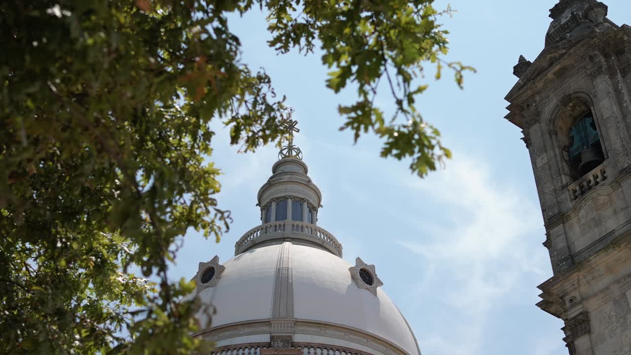 cúpula del santuario de sameiro, enmarcada por árboles exuberantes, contra un cielo azul, braga