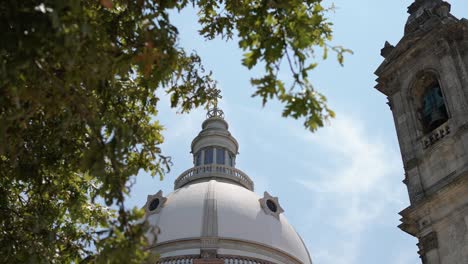 cúpula del santuario de sameiro, enmarcada por árboles exuberantes, contra un cielo azul, braga