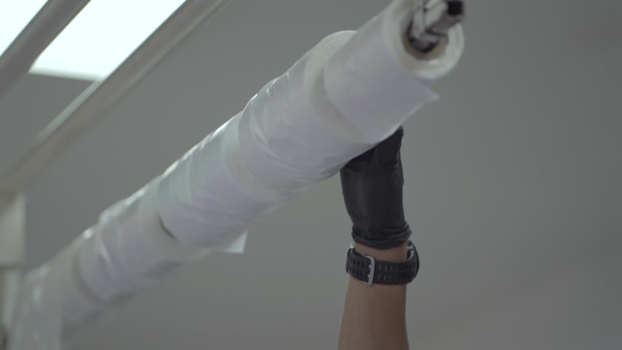 A person holds roll of white plastic bags wrapped around a stick in supermarket