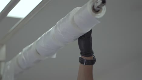 a person holds roll of white plastic bags wrapped around a stick in supermarket