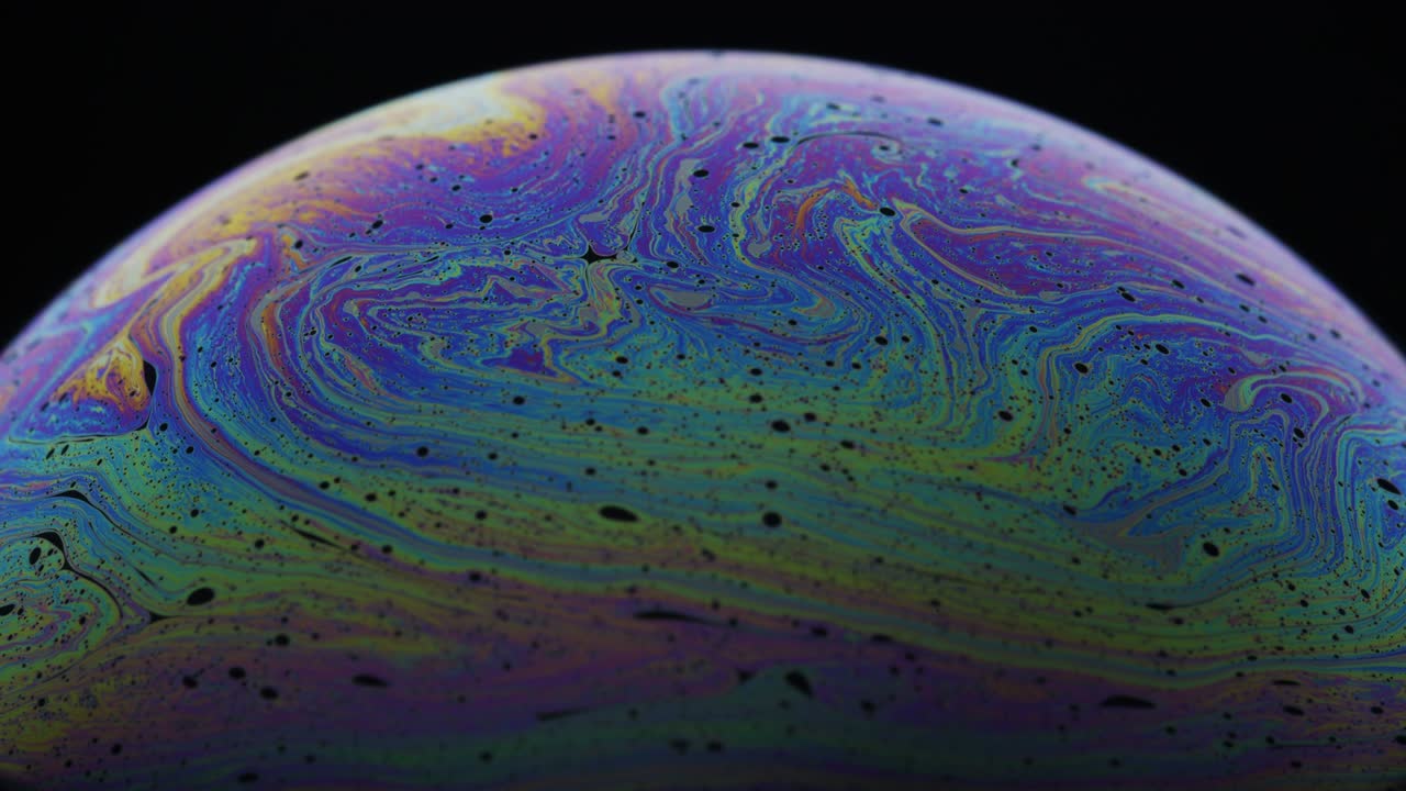 remolinos coloridos y burbujas negras a lo largo de la superficie de la película del jabón