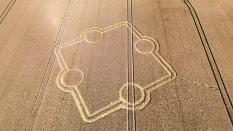 Aerial-view-descending-towards-stone-henge-crop-circle-on-rural-golden-ploughed-farmland