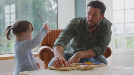 padre con síndrome de down hija jugando un juego con una carta de madera en casa juntos