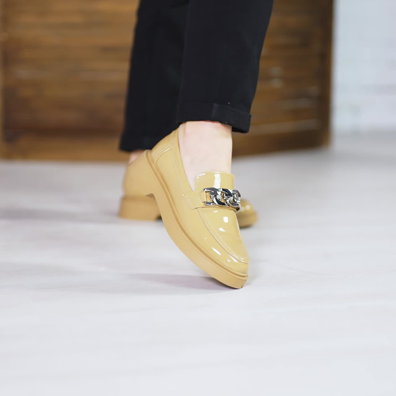 Presentation of beautiful new beige shoes with silver chain decoration. Lady model in black jeans demonstrates footwear. Close up