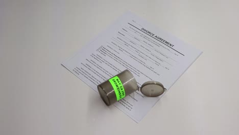 persona tomando un puñado de pastillas para dormir luego recoge un arma de fuego negra con papeles de divorcio dejados visibles en la mesa