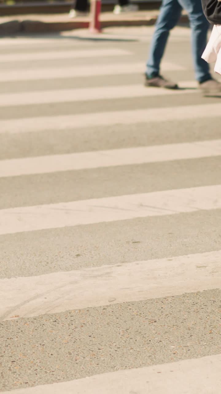 business commuters crossing zebra crosswalk midday, executives in trench coats and heels stride past couriers in sneakers, papers and briefcase visible, brisk urban pace, clicking heels and rhythmic