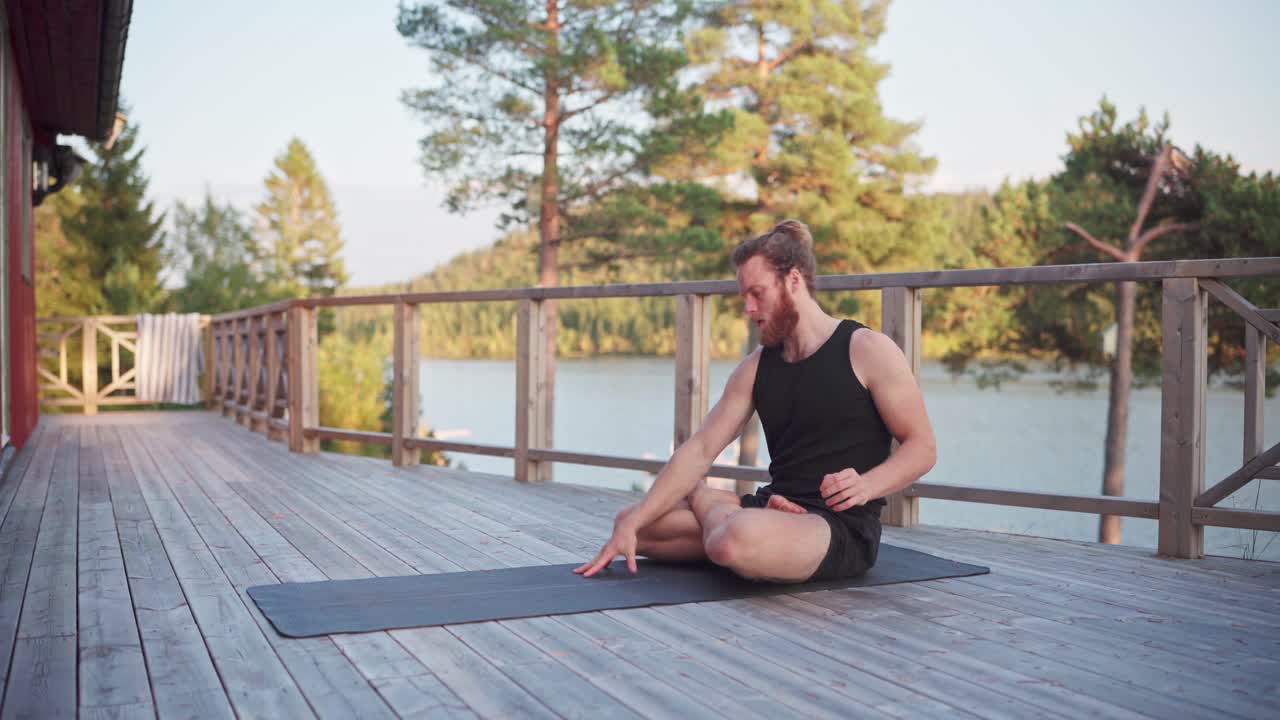 hombre haciendo ejercicios de yoga en la veranda de la cabaña por la mañana