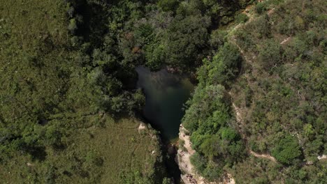 aerial-view-of-Poço-das-Esmeraldas-in-Chapada-dos-Veadeiros-Goiás-Brazil-green-water,-sunny-day,-waterfall,-rocks-and-cerrado