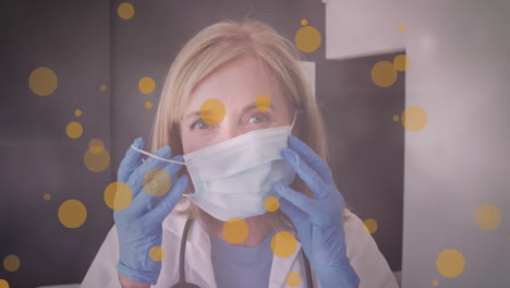 animación de manchas amarillas sobre una doctora caucásica poniendo una máscara facial