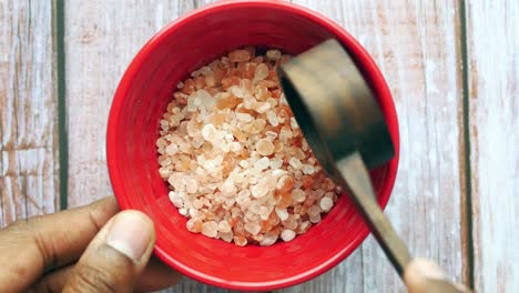 himalayan pink salt in a red bowl with wooden spoon