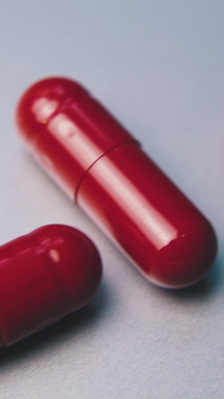 small line of bright shining red medical capsules lying on clean white surface extreme close view