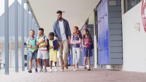 maestro masculino diverso y escolares felices caminando en la escuela