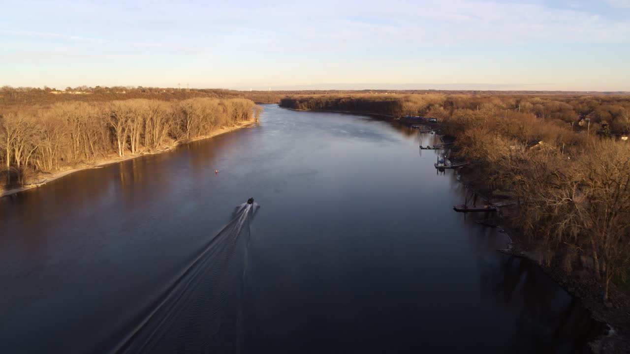 toma aérea, siguiendo un bote a lo largo del río mississippi en minnesota, justo antes del atardecer