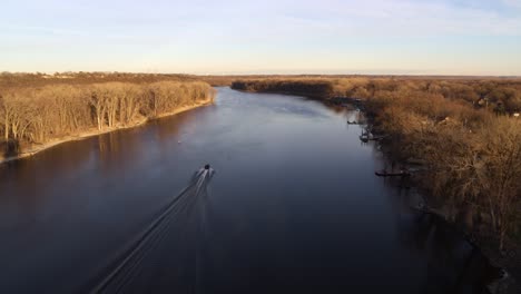 aerial shot, following a boat along the mississippi river in minnesota, just before sunset