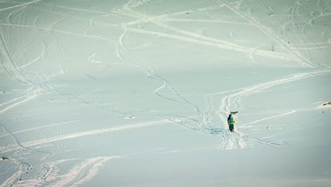 Long-lens-shot-of-three-people-and-their-dog-hiking-through-the-snow