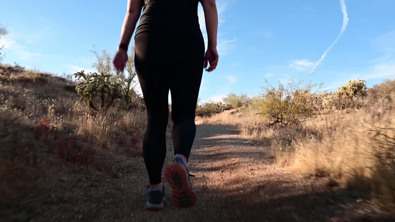 ángulo bajo de mujer caminando por el sendero del desierto