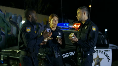 and colleagues from police talking with smiles and having break at patrolling on dark street