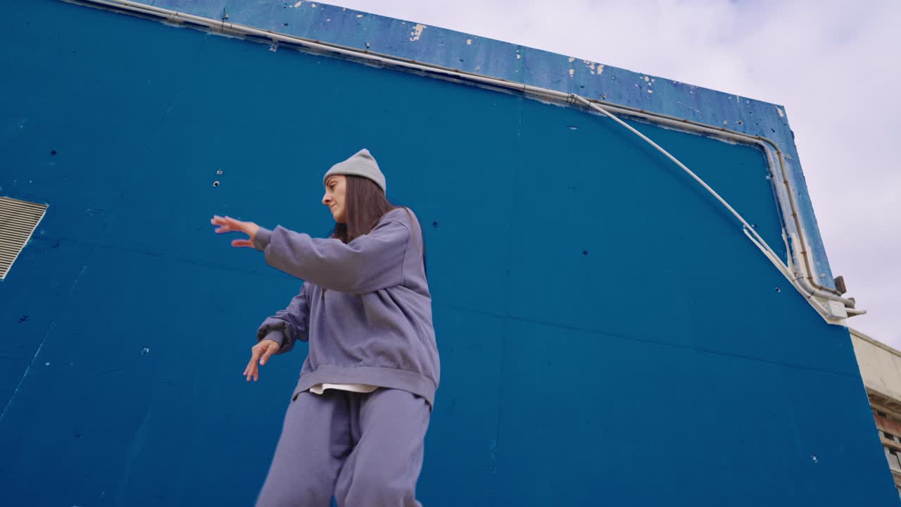 Woman dancing in front of a blue wall