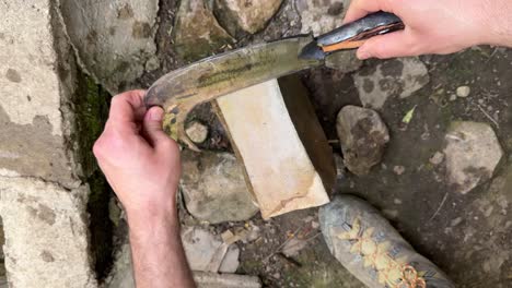 sharpening of agriculture tool blade in a traditional persian arabian turkish style hand made natural sharpener stone to prepare crescent blade to cut wheat rice in middle east gardening in iran