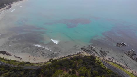 Drone-Aéreo-Revela-Una-Carretera-Oceánica-Azul-Claro-En-Un-Día-Nublado