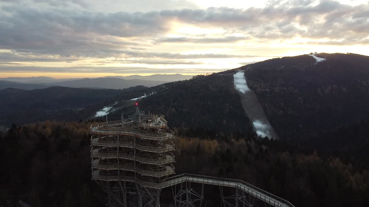 sunset and a huge wooden viewing point in mountains (drone video)