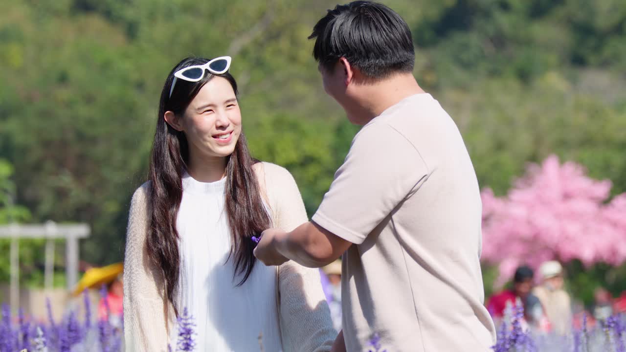 Smiling couple walk and laugh together in bright outdoor flower garden with gentle camera movement
