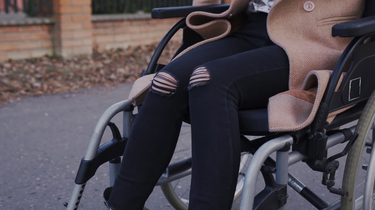 알아보기 힘든 장애인 여성이 휠체어 바퀴를 돌려 도시를 돌아다닌다