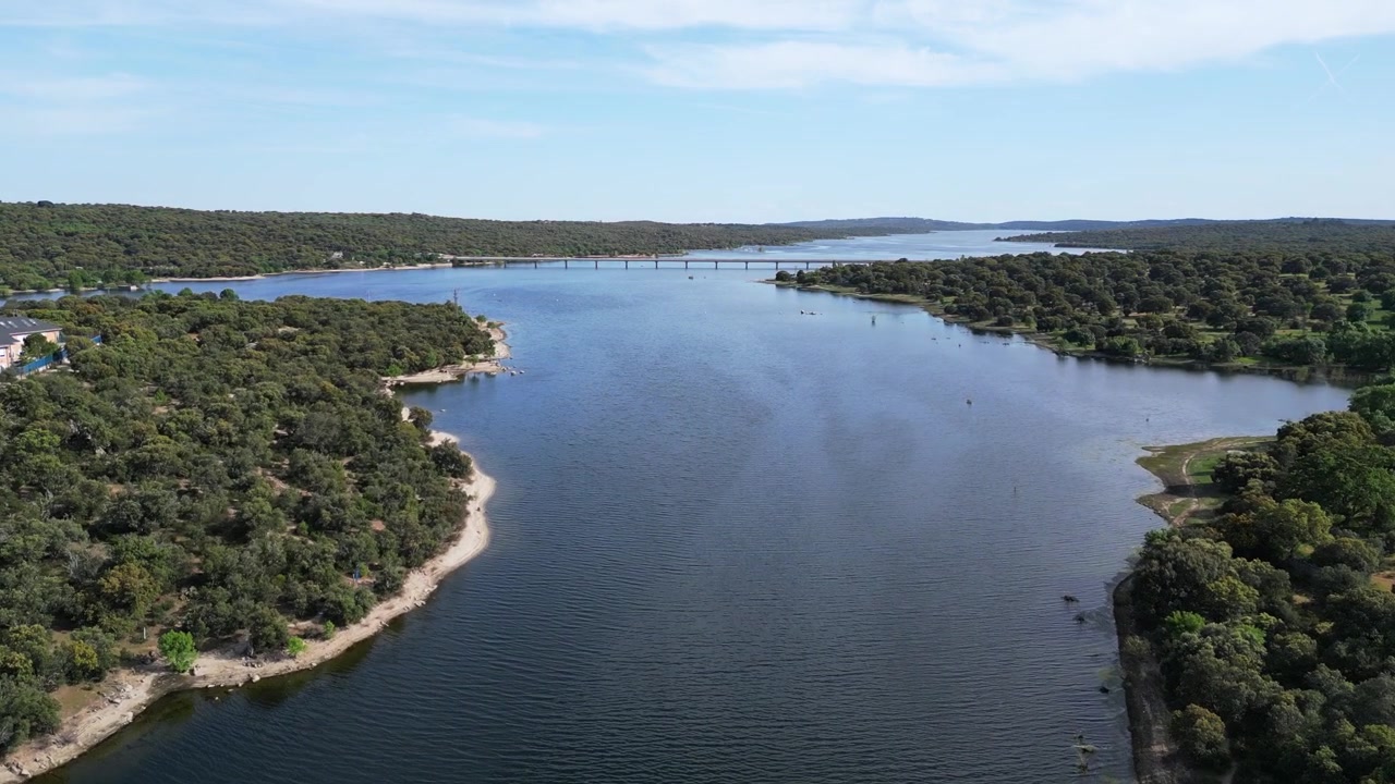Un lago sereno si estende in lontananza con un ponte che collega le rive boscose. Ideale per contenuti di natura e viaggi.