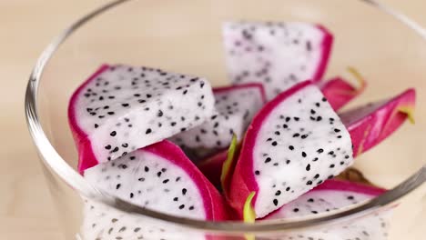 Hand picking dragon fruit slices from bowl