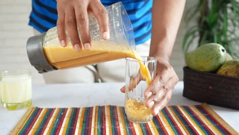 pouring mango smoothie into a glass