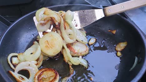 chopped white onions being cooked and flipped in pan outside