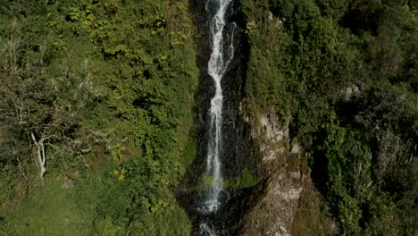 tilt-down through virgin waterfalls flowing from lush valley in baños de agua santa city, ecuador