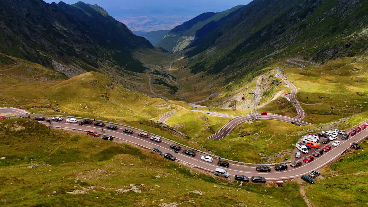 Numerous cars stand along the road in the mountains. Travelling by the famous Transfagarash highway in Romania. Aerial view