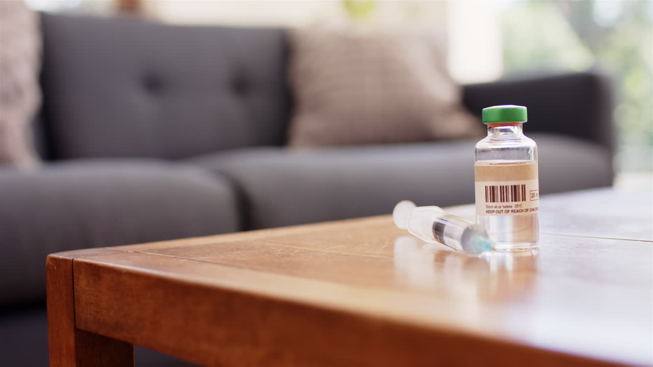 Syringe and vial on table in living room, ready for medical use, copy space