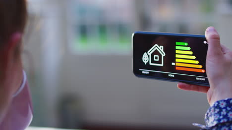 close up of woman with app on mobile phone to measure household energy efficiency at home - shot in slow motion