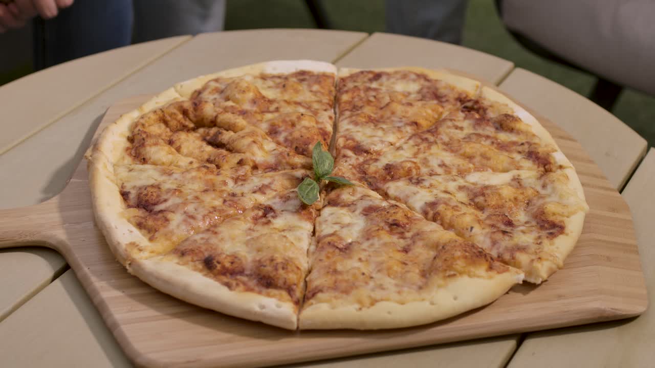 Vista dall'alto di un gruppo di amici che si protendono insieme per prendere fette di pizza calda e filante da un tagliere di legno durante una festa