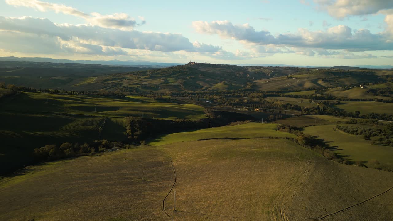 Veduta aerea grandangolare di un vibrante paesaggio toscano arancione e verde che si estende sotto un cielo mozzafiato