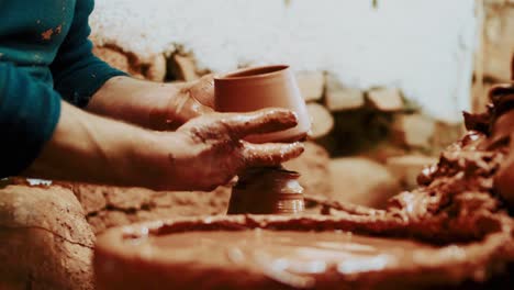 craftsman detaching handmade clay cup from pottery wheel in workshop, close up