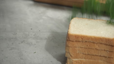 fresh dill is placed on countertop next to stack of white bread slices