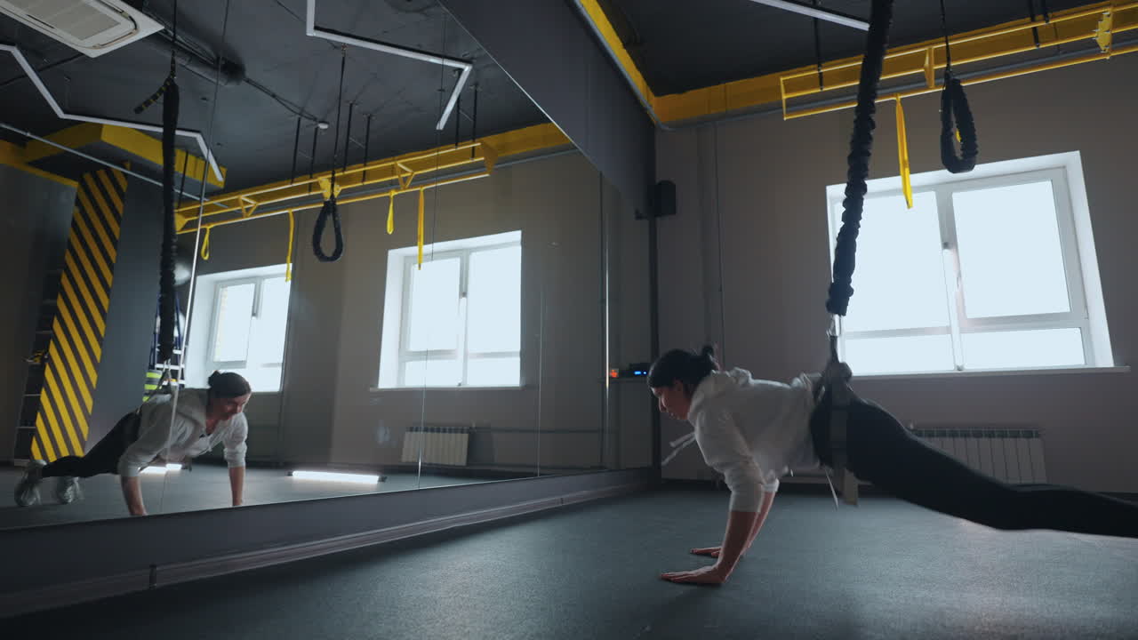 운동 선수 는 서스펜션 시스템 을 사용 하여 현대 체육관 에서 총 저항 운동 을 하고 있다
