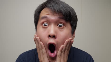 근접 촬영은 아시아 남자의 얼굴을 드러니다. 그의 눈은 놀라움으로 넓어지고, 그는 집중적으로 앞으로 쳐다보고 있습니다.