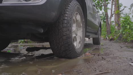 car parked in muddy ground with rain puddles