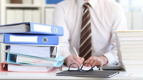 businessman counts on calculator and writes data with documents