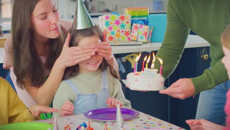 Una-Chica-Soplando-Velas-En-El-Pastel-De-Cumpleaños-En-Una-Fiesta-Con-Padres-Y-Amigos-En-Casa