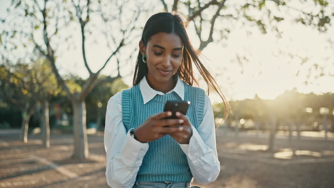 Giovane donna che usa lo smartphone all'aperto sotto il sole
