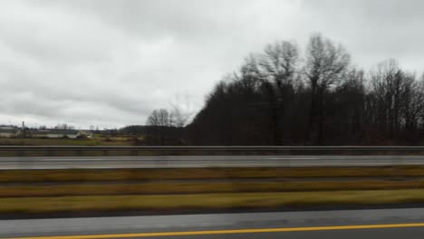 a footage of driving on a highway with fields and overcast skies in the background